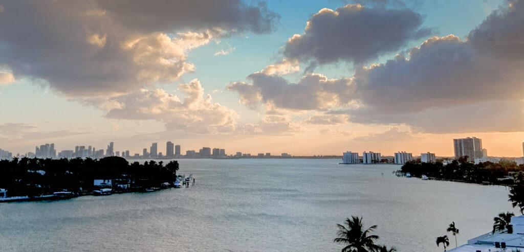 Yacht anchored in coastal bay at sunset with city skyline in the distance