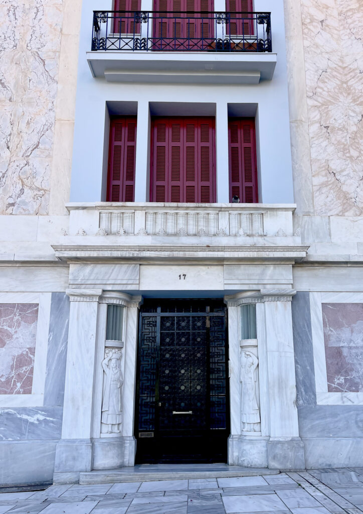A European Mediterranean marble building closeup with black doors red doors marble statues marble terrace marble walls marble street