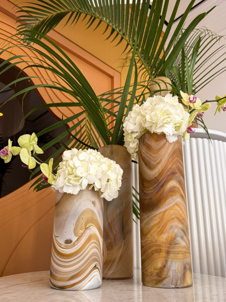 Marble vases with flowers rest on a marble pedastal