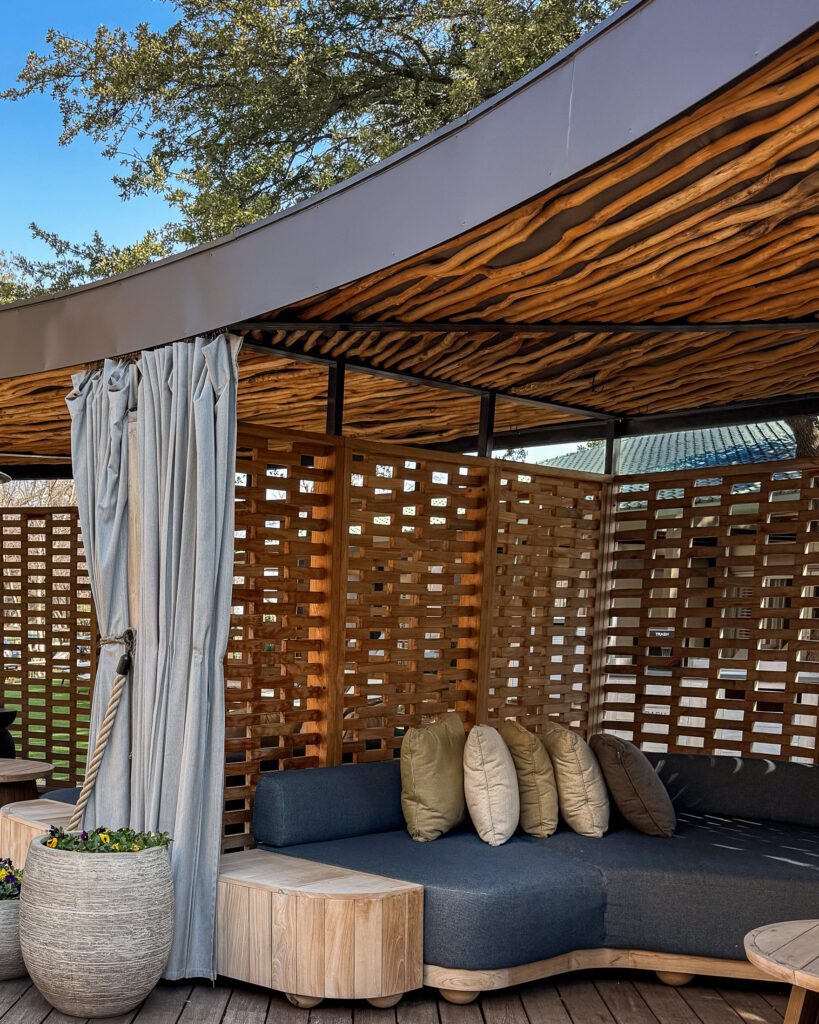 Curved wooden cabana pergola with blue couch and curtains