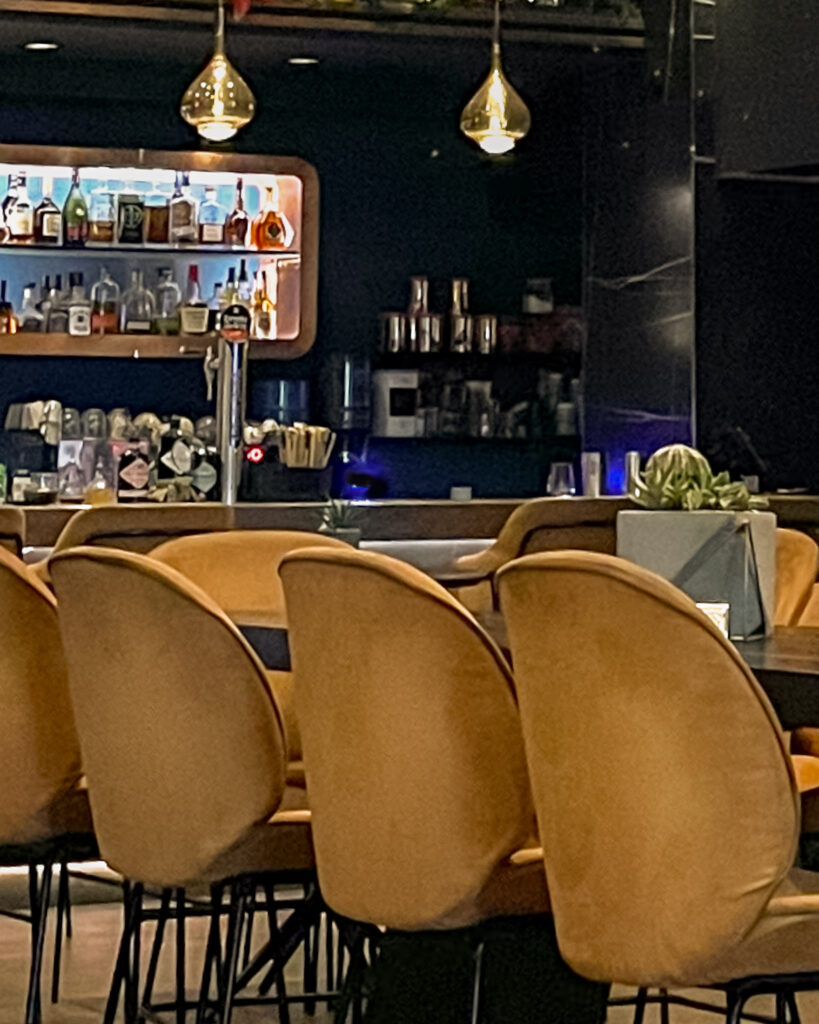 Wood table with bar counter and linear pendant lights in modern lounge space