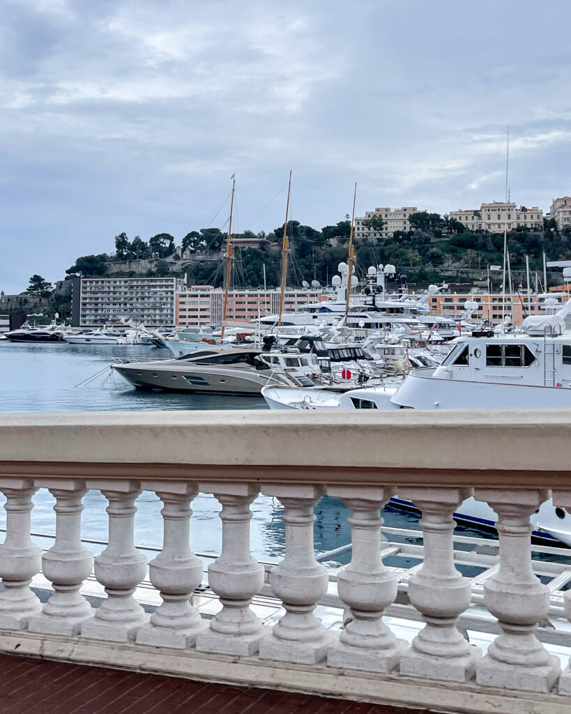 Balcony view of stone balustrade overlooking yachts in marina with buildings in distance